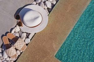 rebord de piscine avec ton et chapeau posés au sol